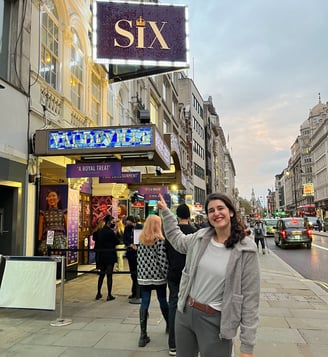 a woman standing on a sidewalk next to a london theatre