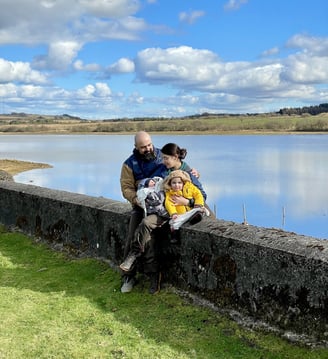 a family of four sitting on a stone wall