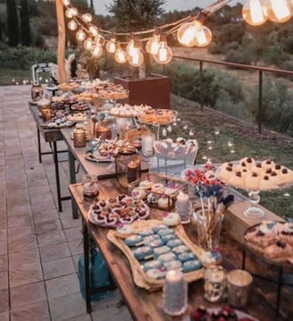 Buffet sucré en plein air avec desserts maison, vaisselle vintage et décoration lumineuse pour une f