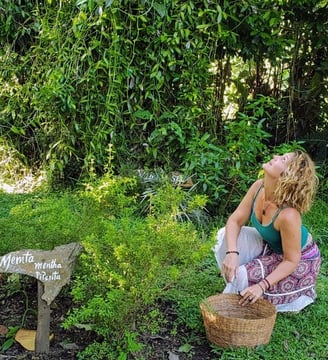 a crouching woman holding a basket in the middle of nature and looking upwards