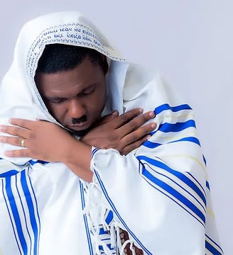 Nacee in a white shirt covered with a stripped blanket.