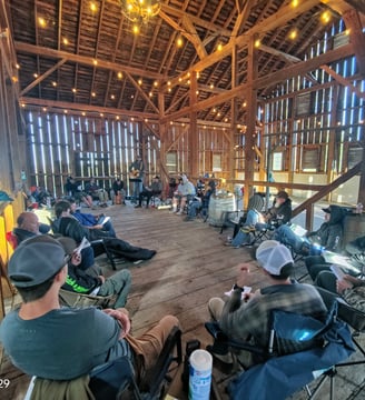 a group of people sitting in chairs in a barn