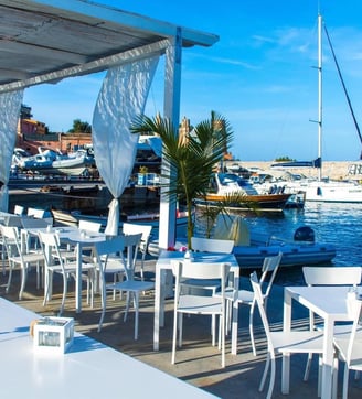a restaurant with tables and chairs and a boat in the water