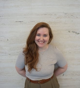 a woman in a gray sweater and brown belted pant