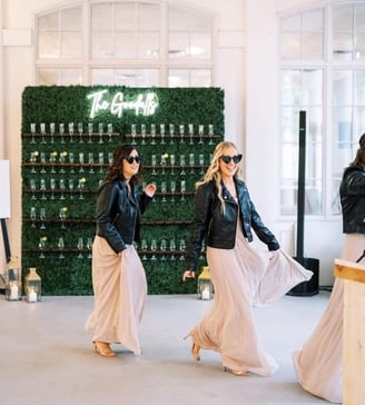  Bridesmaids walking past the grass champagne walls behind them.