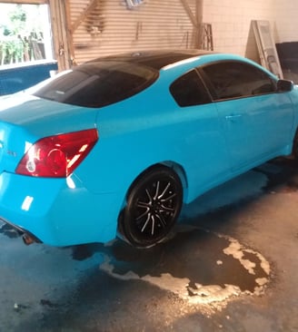a custom blue car in a garage with a custom blue car with black custom rims