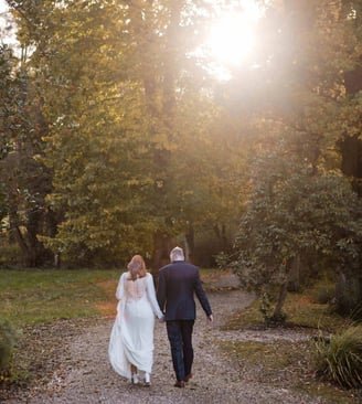 Bride and groom walk towards a sunset on their wedding day