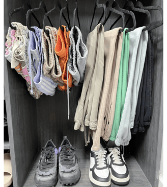 Colorful shorts and pants neatly hung above sneakers in a modern organized closet.