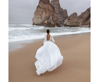 a woman in a white dress is walking along the beach