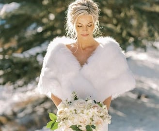 a bride in a white wedding dress with a fur stoler