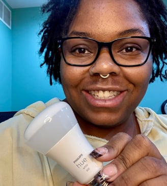 Ashley smiling and holding a philips hue lightbulb