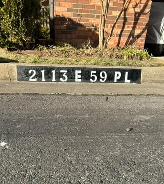 Address "2113 E 59 Pl" painted in black and white on curb.