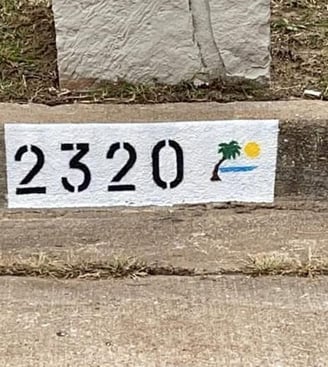 Address "2320" painted with a palm tree at the beach.