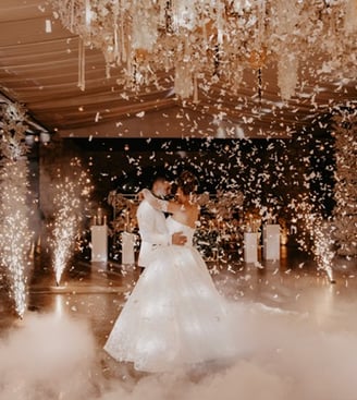 Novios bailando el vals el día de su boda rodeados de mariposas de papel y pirotecnia fria muy feliz