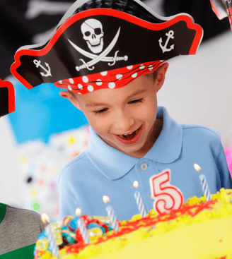 Un enfant déguisé en pirate devant son gâteau d'anniversaire