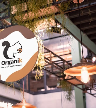 Branding para cafeteria:  logotipo en letrero de entrada rodeado de luces y plantas.