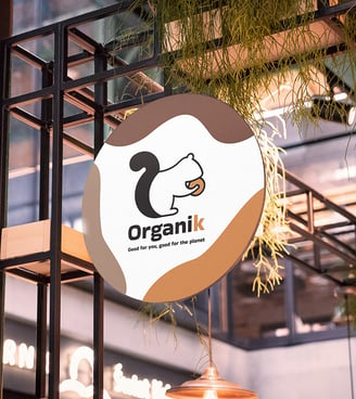 Café branding: squirrel logo displayed on entrance sign amid ambient lighting and greenery.