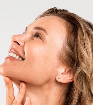 Woman looking up, touching her chin, showcasing a refined jawline.