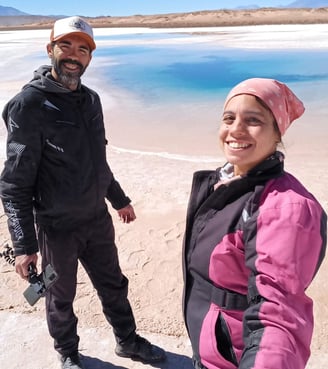a man and woman standing on a beach cono de arita puna atacama salar ojos de mar salta