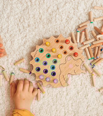 a child's hands playing with wooden pegons
