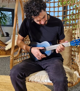 a man sitting on a swing chair with a guitar