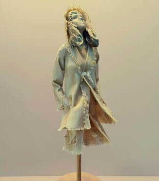 Clay and canvas sculpture of a female figure gazing upwards, wearing windswept, ragged clothes.