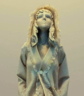 Clay and canvas sculpture of a female figure gazing upwards, wearing windswept, ragged clothes.