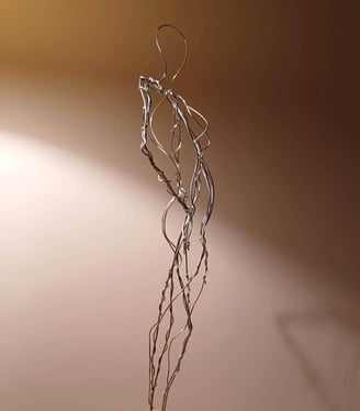 A wire sculpture of a complete female figure, standing with hands on hips