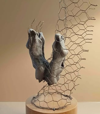 A sculpture of two female torsos, back to back, surrounded by wire netting, painted blue-greys