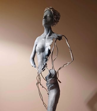 A complete sculpture of a standing female figure, part clay, part wire, hands on hips