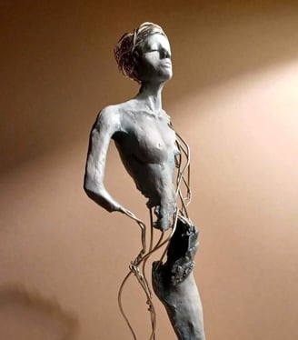 A complete sculpture of a standing female figure, part clay, part wire, hands on hips