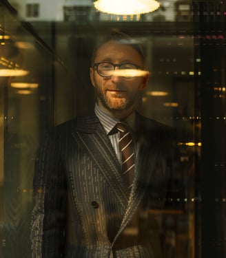a man in a suit and tie standing in front of a glass wall