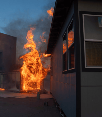 IBHS research center testing fire prevention for properties showing an engulfed structure next to another building catch fire