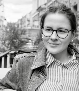a woman in glasses and a jacket is sitting on a bench