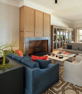 Seating area at Villa La Gratitud with designer sofas, fireplace, and garden views through windows.