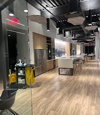 A large open-style kitchen at an office building with a janitorial cart in front of it.