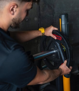 Antrenor montând o greutate pe bara de antrenament, ilustrând atenția la detalii