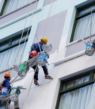 um grupo de pintores pintando uma fachada de um condominio