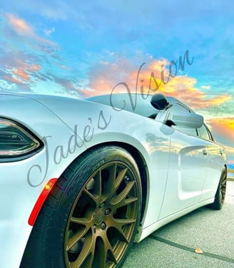 A white Dodge Charger with chrome hubcaps under a pink and blue cloudy sky on the Blue Ridge Parkway