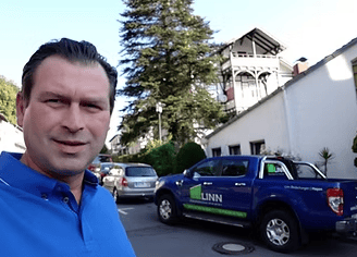 a man in a blue shirt is standing in front of a blue truck