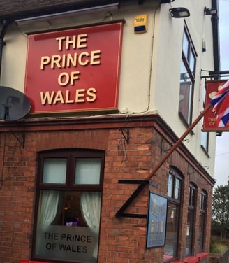 a flag flying in front of a pub with a sign saying THE PRINCE OF WALES