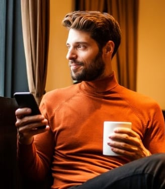 a man sitting on a couch holding a cup of coffee