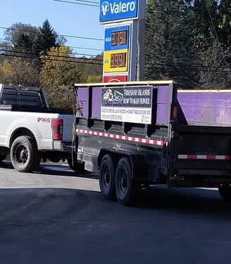 A Truck pulling a purple dump trailer branded for TI Dump Trailers