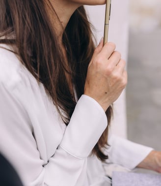 a woman touching her chin with the pen in her hand