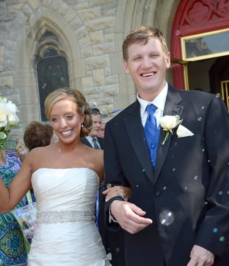 a bride and groom are walking our from the church and bubbles around them