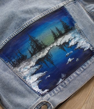 a denim jacket with a painting of a blue sky