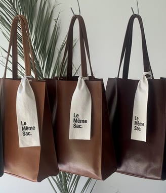 Bolsos Tote colgados en fila con degradé de colores, destacando la belleza del cuero y la elegancia 