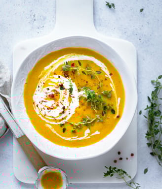 anti-inflammatory vegetable soup in white bowl with herbs and pomegranate seeds