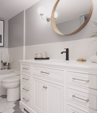 a white and gray bathroom with a large wood mirror
