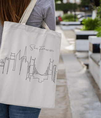 a woman walking down a sidewalk with a tote bag